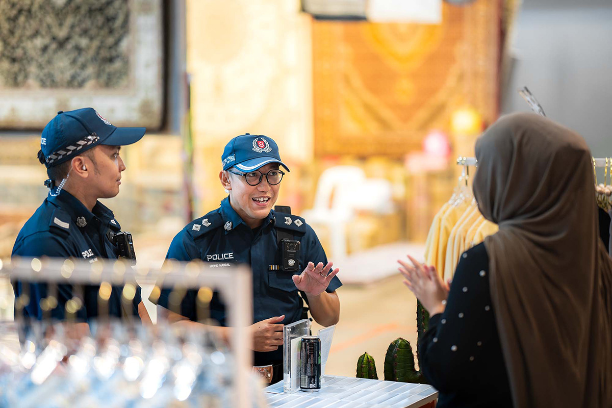 DSP (NS) Haiqal and Sgt (NS) Haikel having a baju moment with a vendor, proving that good relationships are always in style at the Bazaar Raya Geylang Serai.